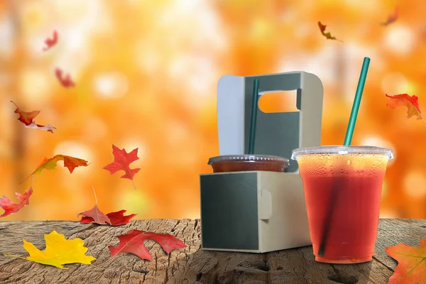 Lezzetli espresso ve paket kahve, tutacakta fincanlar, eski ahşap zeminde kahve bardakları ve sonbahar akçaağaç yaprakları ahşap bir masada.