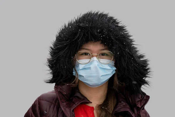 Ein Teenager mit Winterjacke und Kapuze, der eine schützende Gesichtsmaske trägt. Bild isoliert auf grauem Hintergrund — Stockfoto