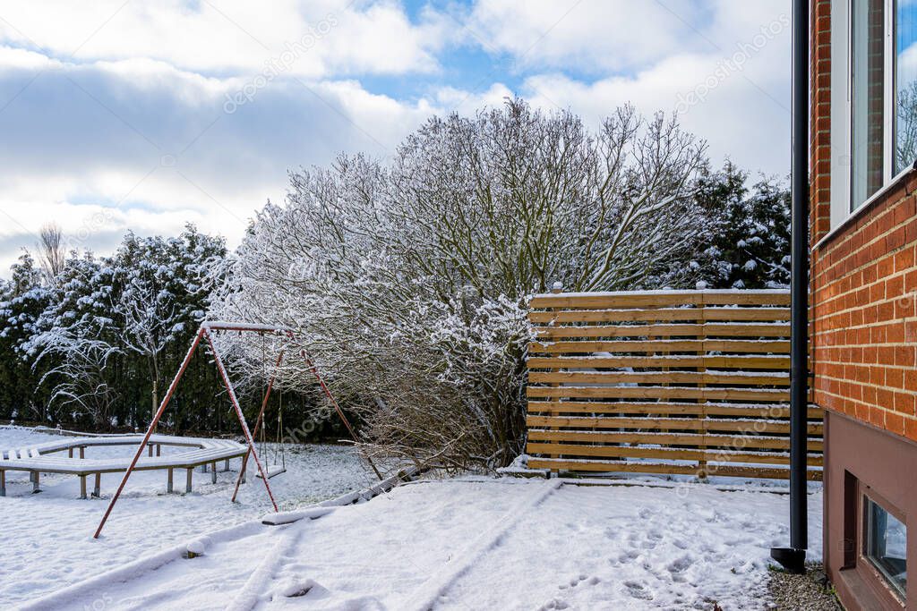 Winter picture of a tree and a wooden fence in a garden. Picture from Scania, Sweden