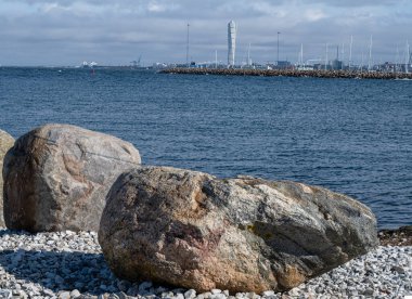 Ön planda dalga kırıcı olarak büyük kayaları olan bir okyanus körfezi. Fotoğraf: Malmö, İsveç