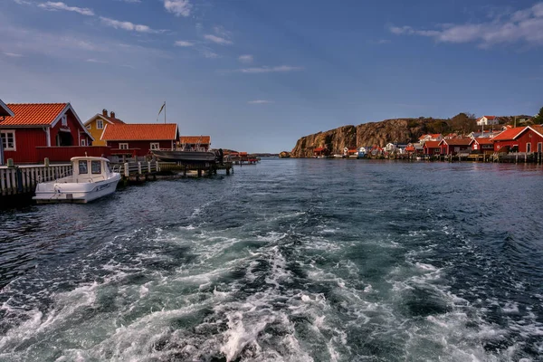 Un pintoresco pueblo de pescadores en la costa oeste sueca. Cabañas tradicionales de mar rojo y un cielo azul en el fondo —  Fotos de Stock