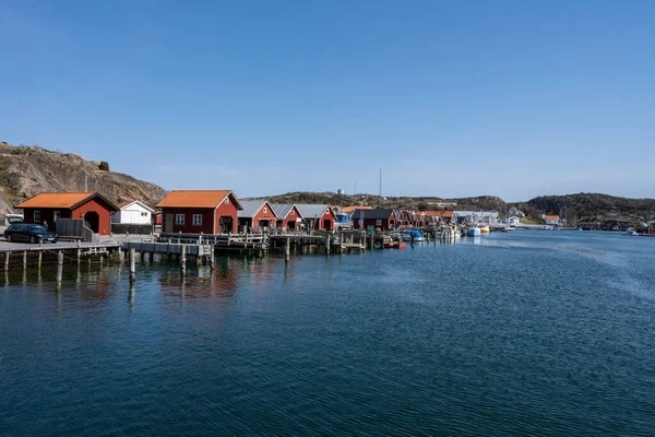 Un pittoresco villaggio di pescatori sulla costa occidentale svedese. Tradizionali capanne rosse e un cielo blu sullo sfondo — Foto Stock