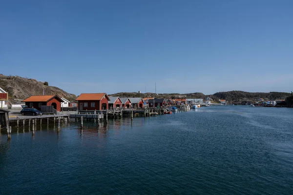 Un pintoresco pueblo de pescadores en la costa oeste sueca. Cabañas tradicionales de mar rojo y un cielo azul en el fondo —  Fotos de Stock