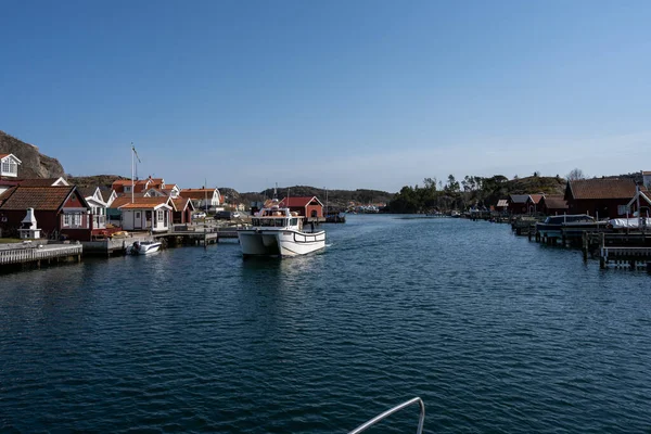 Malebná rybářská vesnice na švédském západním pobřeží. Tradiční červené mořské chaty a modrá obloha v pozadí — Stock fotografie