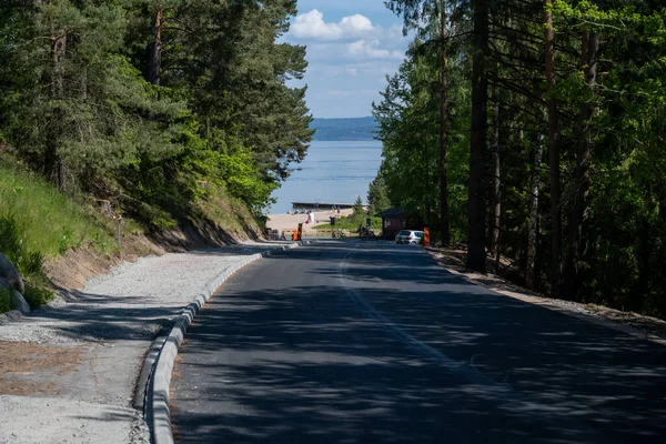 A newly paved road down to Lake Vattern a hot summer day. Picture taken from the shade of pine trees. Domsand beach, Habo — Stock Photo, Image