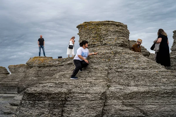 La gente disfruta de una hermosa formación de piedra caliza en una línea costera del Mar Báltico. Un cielo dramático en el fondo — Foto de Stock