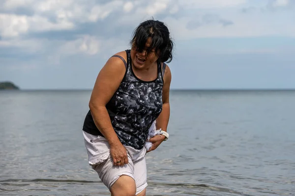 Een Aziatische vrouw van middelbare leeftijd aan een meer. Zachte, wazige achtergrond — Stockfoto