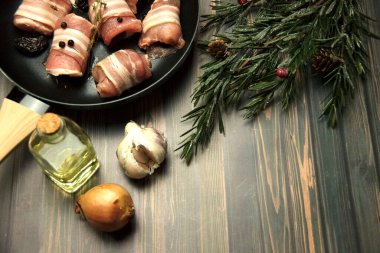 Fresh, raw, uncooked pork rolls in frying pan with Christmas decoration. Cooking background.