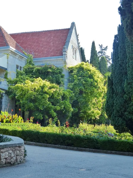 Evin ön tarafı palmiye ağaçları ve lianalar yüzünden zar zor görülebiliyor. Kadife mevsimi. Gaspra köyünün alanı (Yalta 'nın bir kısmı, 70 kilometreden fazla bir alan)).