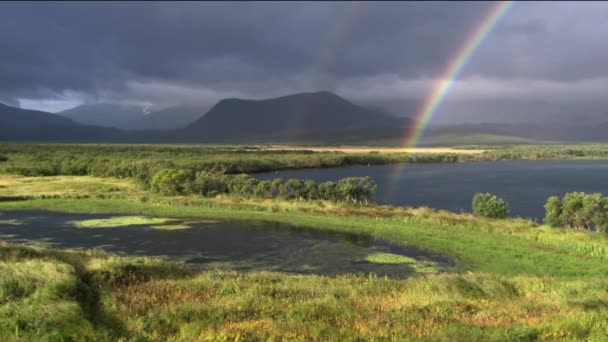 Arco-íris colorido após uma tempestade de primavera no fundo de montanhas, nuvens de tempestade e um lago de floresta. Vida selvagem. — Vídeo de Stock