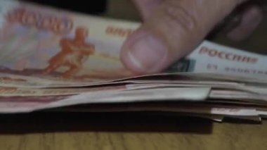 Muhasebeci el ile alınan parayı yeniden hesaplıyor. Rusya Federasyonu 'nun banknotları. Değeri beş bin ruble. Rusça 'daki yazı: 