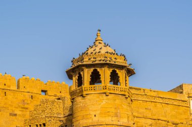 Kuşlar Jaisalmer, Rajasthan, Hindistan 'daki eski şehrin duvarlarında bir minareye tünediler.
