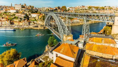 Dom Luiz köprüsünün yanındaki Douro nehrinde ve güneşli bir öğleden sonra Porto, Portekiz 'in eski mahallesinde bir eğlence gemisi.