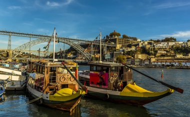 Porto, Portekiz 'deki Dom Luiz köprüsünün yanındaki Douro nehrine demirlemiş turist gemileri güneşli bir öğleden sonra