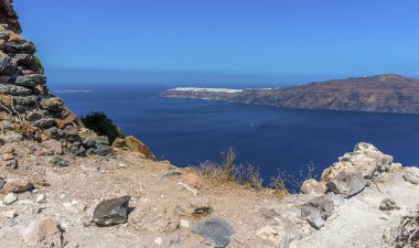 Skaros Kayası 'nın kayalık önplanı Caldera manzarasının önünde yaz mevsiminde Oia' ya doğru.