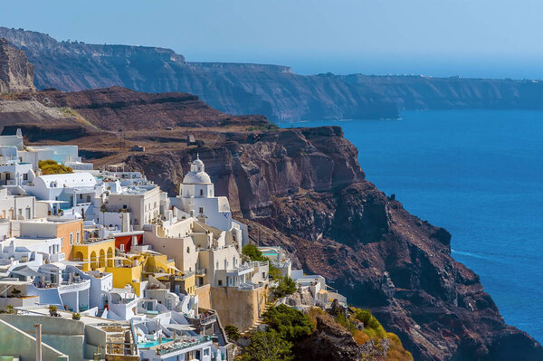 Cliff top buildings in Thira, Santorini contrast with the volcanic background in summertime