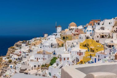 Yel değirmenleri, kubbe kiliseleri ve yazın Santorini 'nin Oia köyündeki göz kamaştırıcı beyaz binalar.