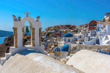 Yazın Oia, Santorini köyündeki çan kuleleri ve mavi kubbeli kiliselerin manzarası