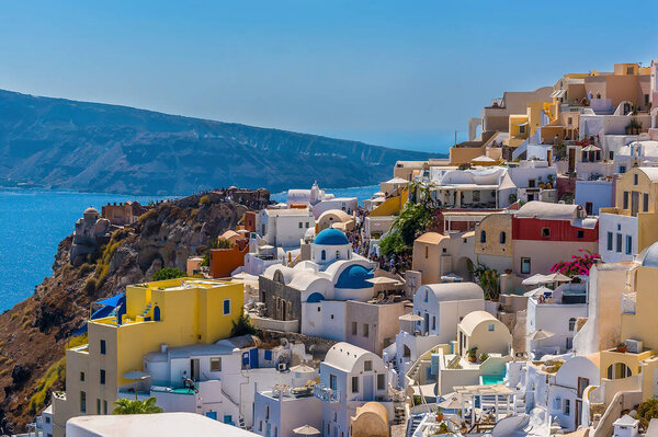 Brightly painted houses and blue-domed churches in the village of Oia, Santorini in summertime