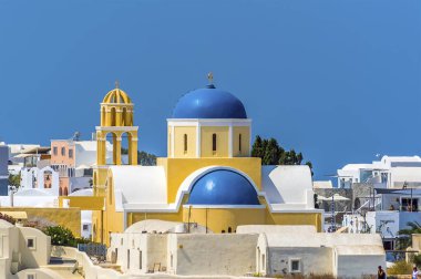Santorini 'de Caldera' nın kıyısındaki Oia kasabasındaki mavi kubbeli, sarı kiliseler.