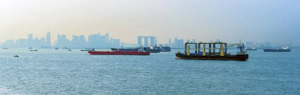 Commercial shipping with Singapore silhouetted in the background in summertime