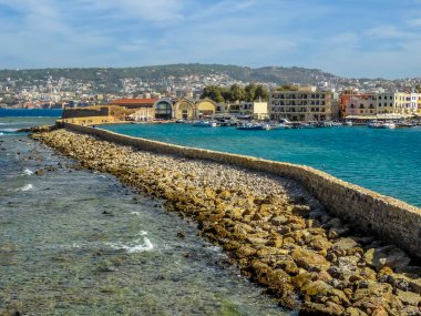 Chania Limanı, Girit 'teki deniz duvarı güneşli bir günde yenilenmiş kayıkhanelere açılıyor.