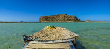 Balos Sahili, Girit 'te, güneşli bir günde turkuaz lagünün kıyısındaki ahşap iskeleden manzaralı bir manzara.