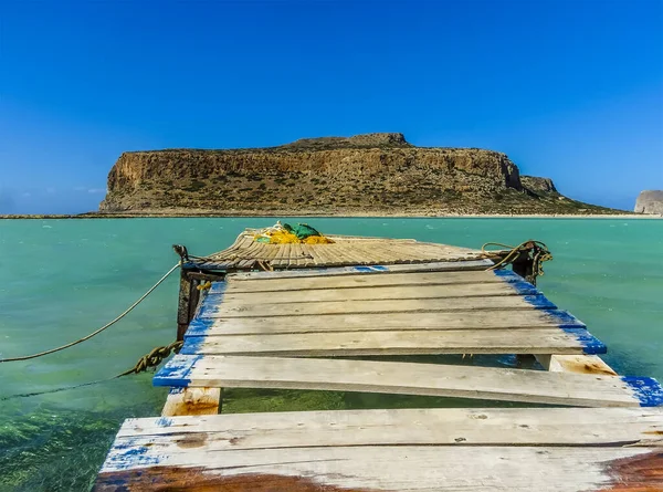 Girit 'in Balos Plajı' ndaki turkuaz gölün kıyısında, parlak güneşli bir günde ahşap bir iskele.