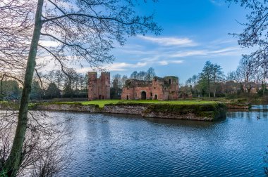 Güneşli bir günde İngiltere 'nin Kirby Muxloe kentindeki şatoya doğru ağaçların arasından bir manzara