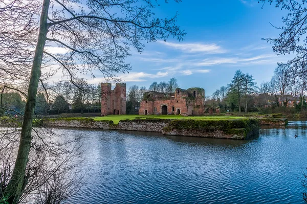 Güneşli bir günde İngiltere 'nin Kirby Muxloe kentindeki şatoya doğru ağaçların arasından bir manzara