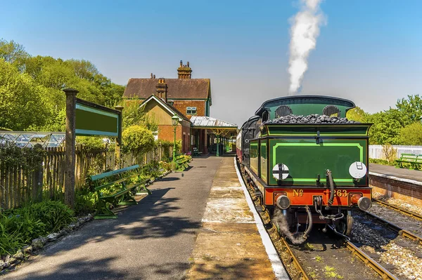 Güneşli bir yaz gününde Sussex, İngiltere 'de bir tren istasyonunda bekleyen bir buhar treni.