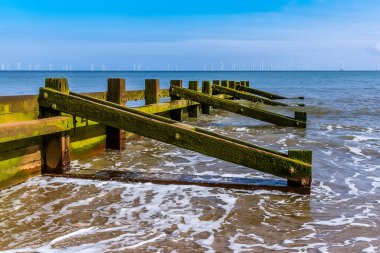 Yazın İngiltere, Skegness plajında, ufukta görünen bir rüzgar çiftliği ile bir Groyne 'un alçak tarafı boyunca bir manzara.