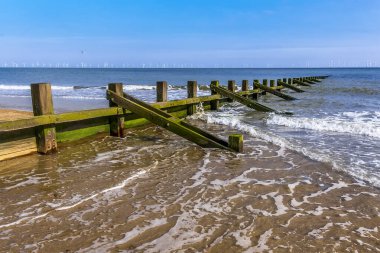 Groyne 'lar yaz aylarında Skegness plajında bir rüzgar çiftliğine doğru denize doğru uzanıyorlar..