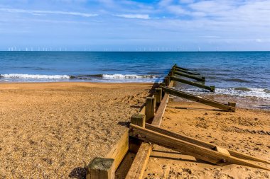 İngiltere 'nin Skegness sahilindeki deniz savunması boyunca bir manzara. Yazın ufukta bir rüzgar çiftliği görünüyor.
