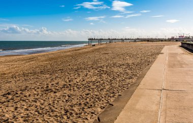 İngiltere 'nin Skegness plajındaki gezinti güvertesi boyunca yaz aylarında iskelenin kalıntılarına doğru bir manzara.