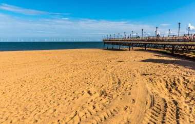 İngiltere, Skegness İskelesi 'nden geriye kalanlar, yaz mevsiminde ufuktaki rüzgâr çiftliğine yönelik deniz ödülüne işaret ediyor.