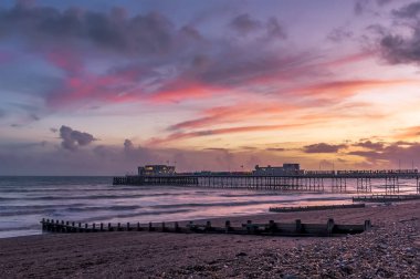 İngiltere 'de Worthing, Sussex' te kıyı ve denizin üzerinde kırmızı ışıklı bulutlar uzanıyor.