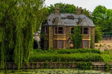 Riverside, Godmanchester, İngiltere 'deki Eski Köprü' den Büyük Okyanus nehrinin kıyısındaki terk edilmiş bir binaya doğru bir manzara.