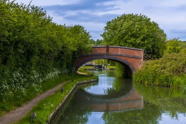 Yazın, Napton, Warwickshire köyünün yanındaki Oxford Kanalı 'ndaki kilit kapılarına doğru giden köprüden bir manzara.
