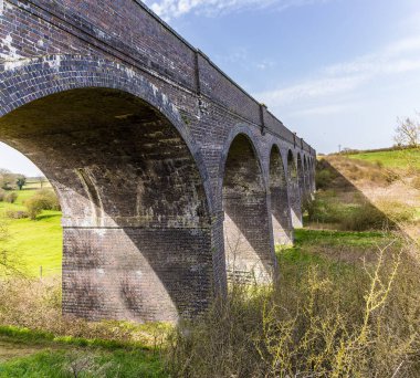 Terk edilmiş Helmdon viyadükünün yanındaki setten parlak bir bahar günü bir manzara.