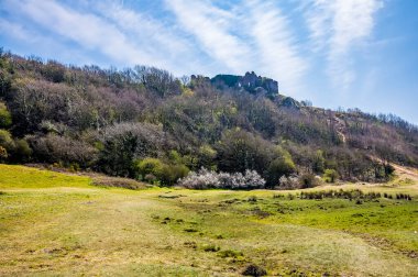 Pennard Hapları 'ndan bir manzara, güneşli bir günde Three Cliffs Bay, Gower Peninsula, Swansea, Güney Galler' e giden yoldaki kalenin yıkıntılarına doğru akıyor.