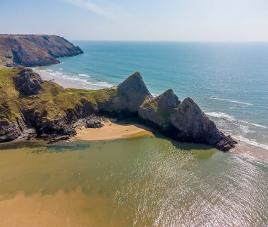 Güneşli bir günde Üç Kayalık Koyu, Gower Yarımadası, Swansea, Güney Galler 'deki üç uçuruma doğru bir hava manzarası.