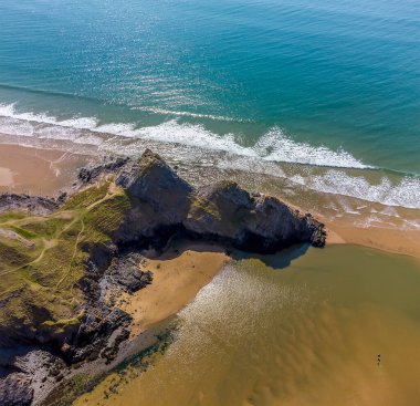 Güneşli bir günde Üç Kayalık Koyu, Gower Yarımadası, Swansea, Güney Galler 'deki üç uçurumun üzerindeki hava manzarası.