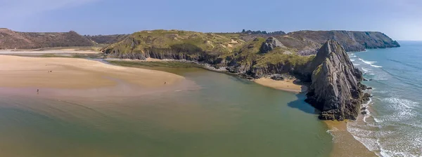 An aerial panorama view of the Three Cliffs Bay, Gower Peninsula, Swansea, South Wales on a sunny day
