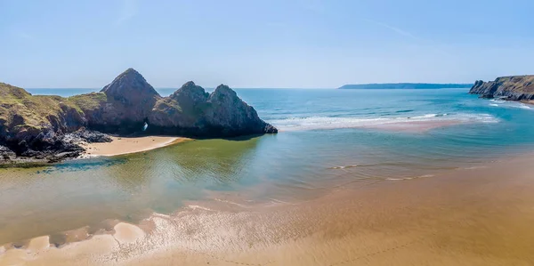 An aerial panorama view across the Three Cliffs Bay, Gower Peninsula, Swansea, South Wales on a sunny day