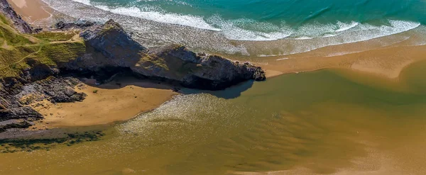 An aerial panorama view above the three cliffs at the Three Cliffs Bay, Gower Peninsula, Swansea, South Wales on a sunny day