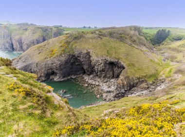 Güneşli bir günde Güney Galler, Tenby yakınlarındaki Pembrokeshire kıyısındaki ıssız bir kayalık koy manzarası