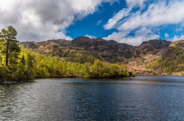 İskoçya 'da bir yaz günü Katrine Gölü' ndeki kayalık kıyı şeridi ve adaların manzarası