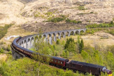 Glenfinnan, İskoçya 'da bir yaz gününde viyadük açısının yükselmesine yardımcı olan bir buhar treni manzarası
