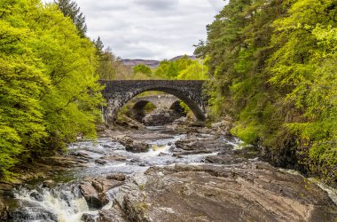 İskoçya 'nın Invermoriston şehrindeki şelalenin üzerindeki iki köprüye bakan manzara